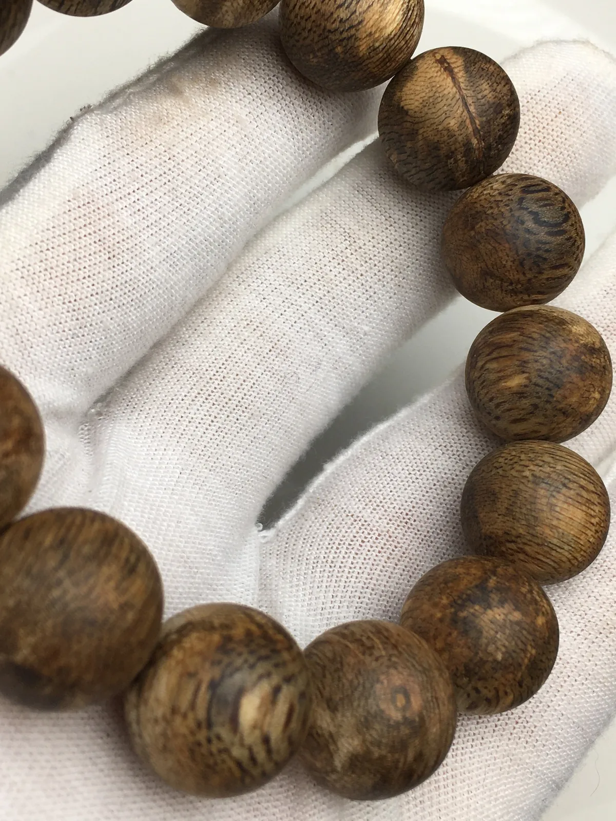 A round-bead rosary bracelet in agarwood, strung to the wrist